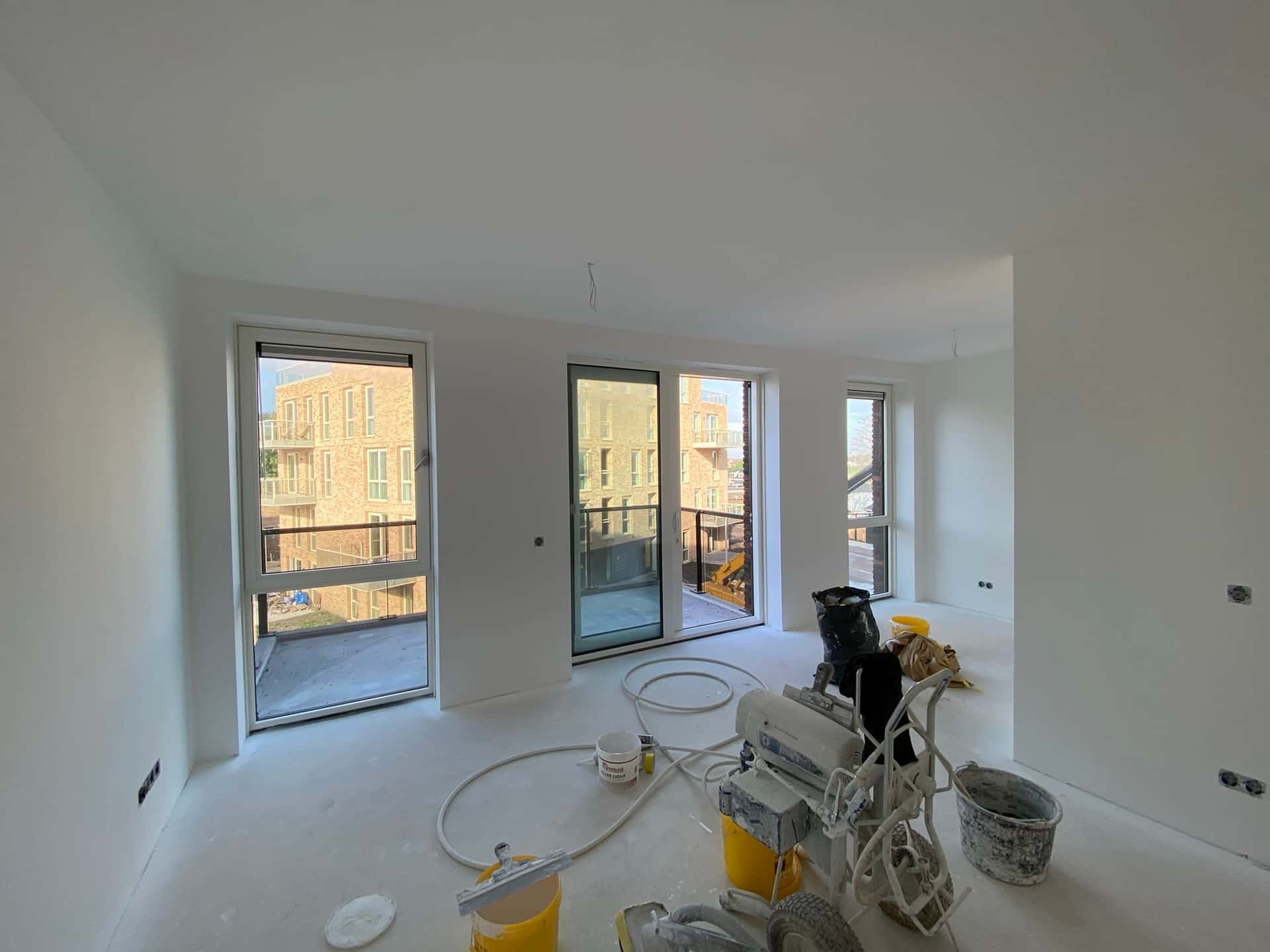 Hoekappartement tijdens latex spuiten met drie grote raampartijen en airless machine