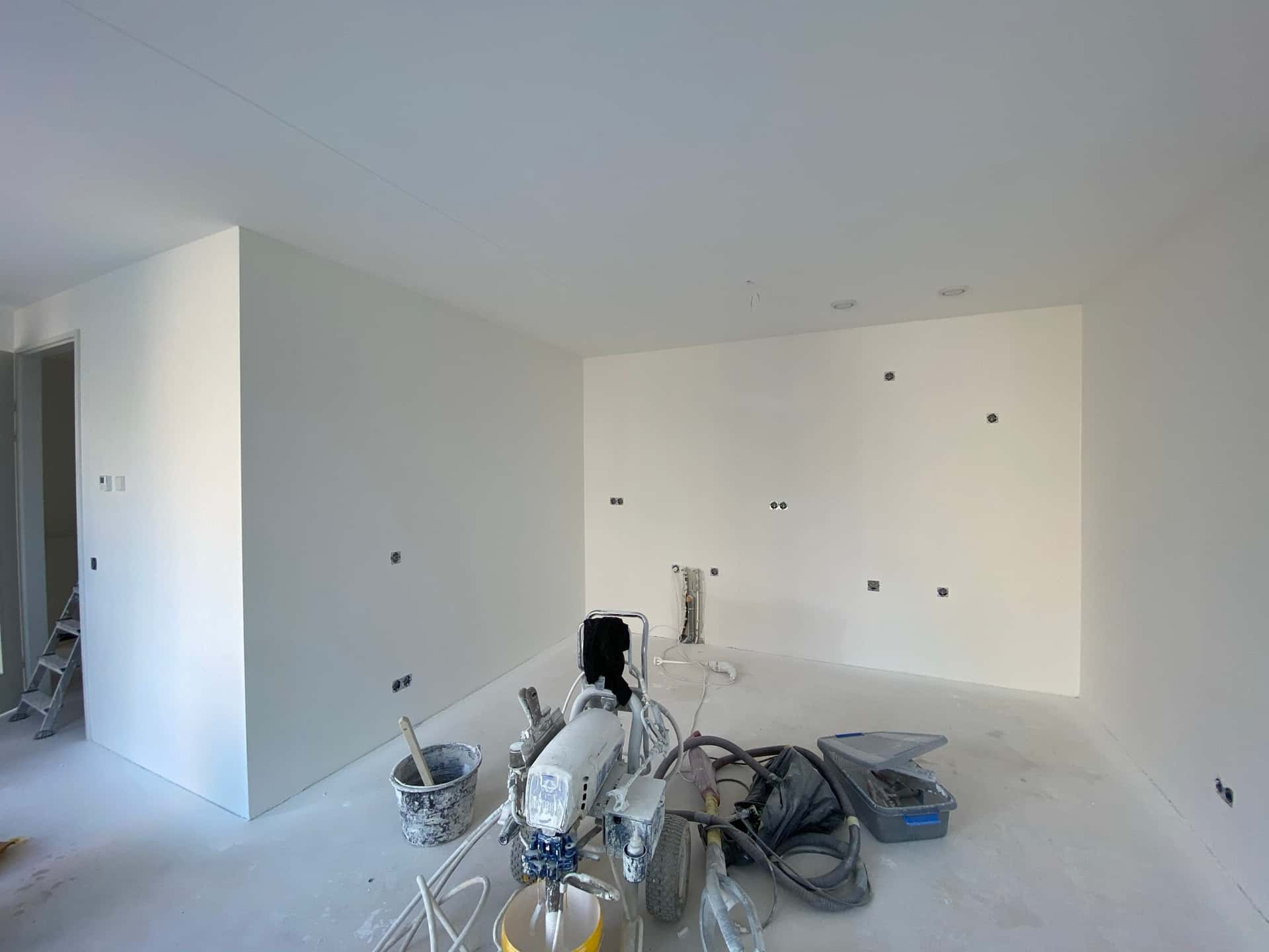 Airless spuitmachine tijdens het spuiten van een nieuwbouw-keukenmuur