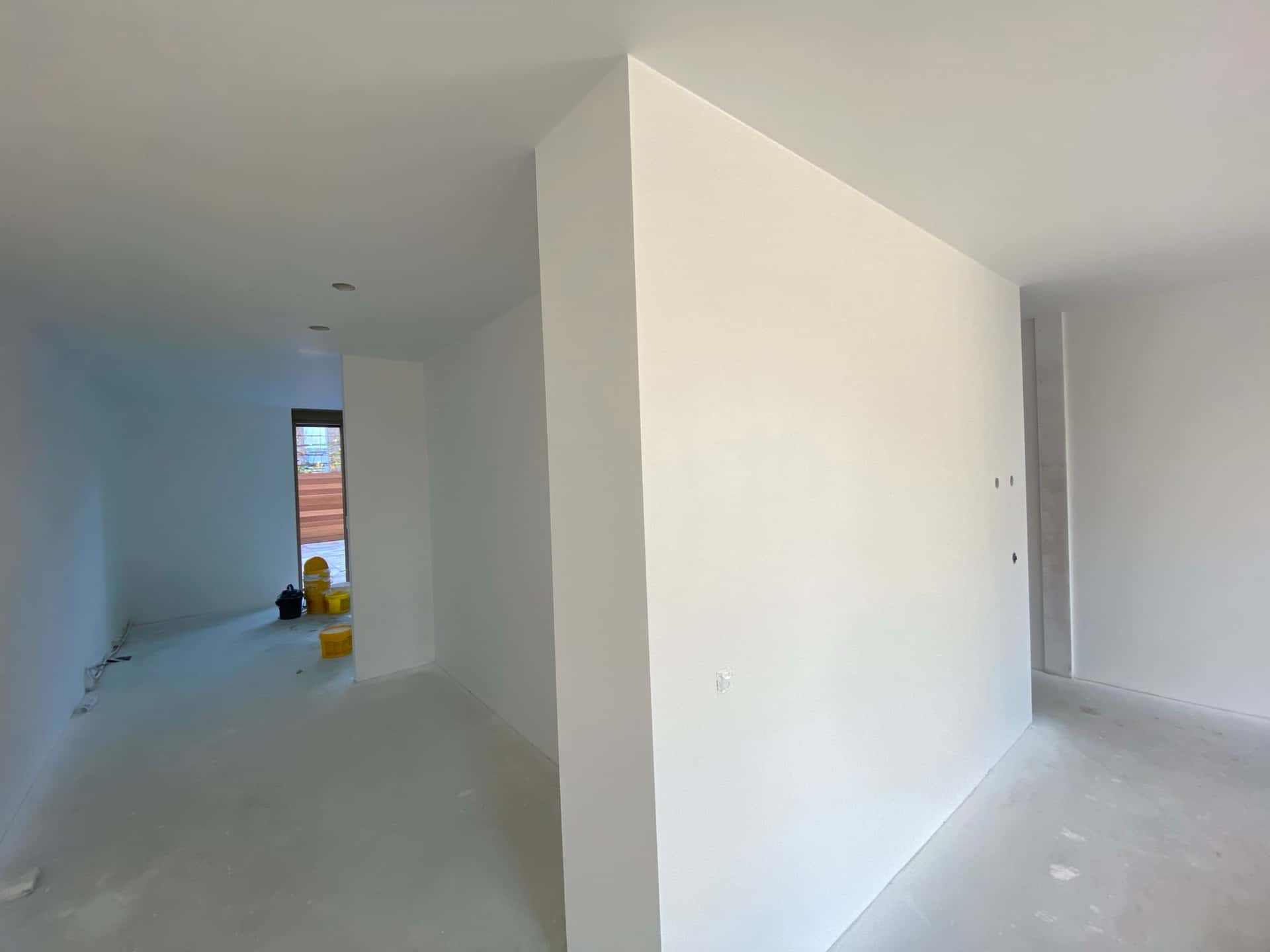 Nieuwbouwruimte volledig gestuct en klaar voor renovlies, tussenmuur en tuindeur achterin